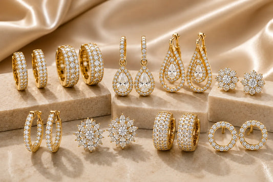 Collection of gold hoop and floral diamond earrings displayed on stone pedestals against a draped silk background.